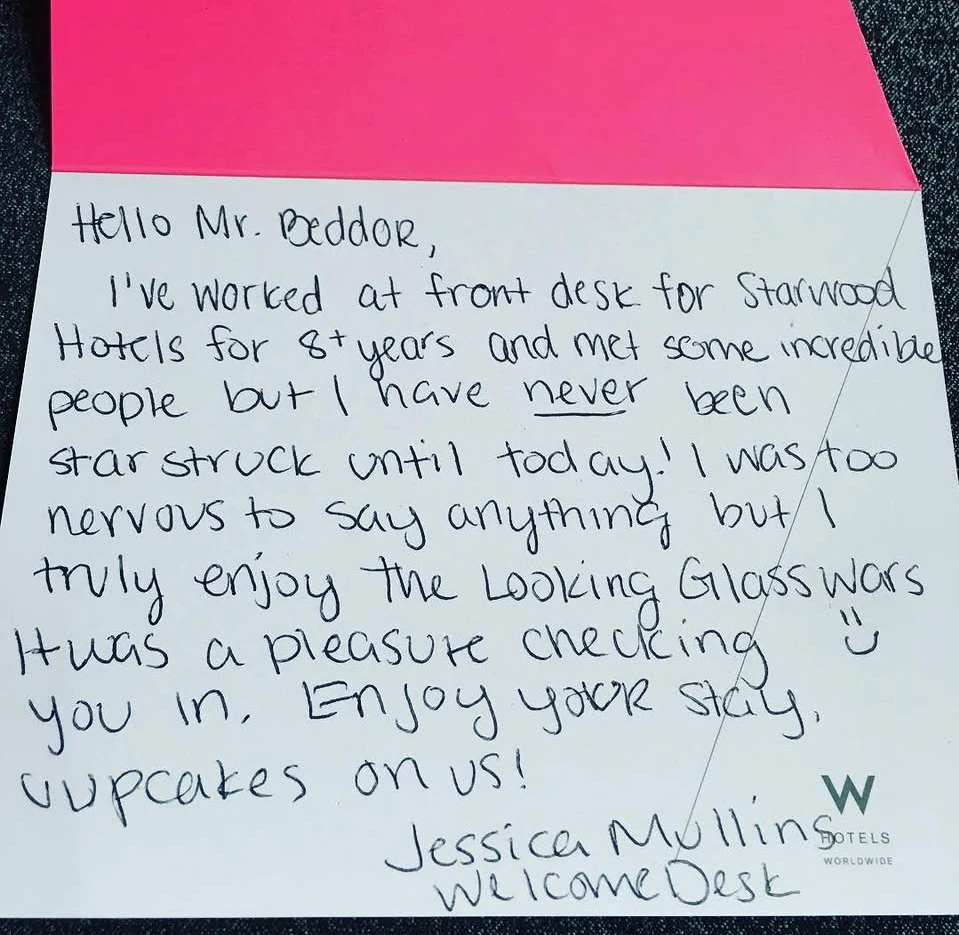 A handwritten card from a hotel welcome desk: after eight
               years on the front desk she had never been star-struck until
               today, too nervous to say anything, but she truly enjoys The
               Looking Glass Wars. Cupcakes on us!