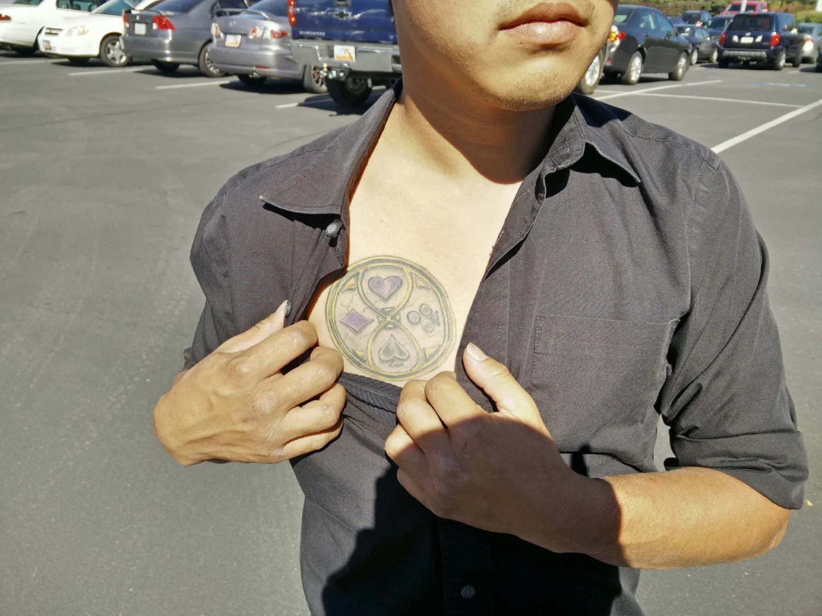 A fan in a car park pulling open his dark shirt to show the
               four-suit emblem of The Looking Glass Wars tattooed across his
               chest in gold, purple and grey.