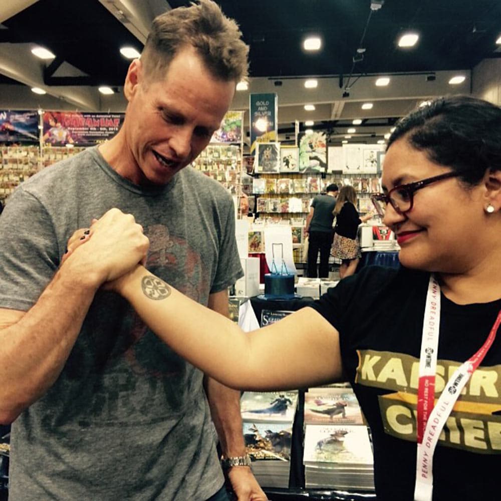 At Comic-Con, a fan in a Kaiser Chiefs T-shirt clasps hands
               with Beddor arm-wrestle style, showing off the four-suit
               emblem of The Looking Glass Wars tattooed on her inner wrist.