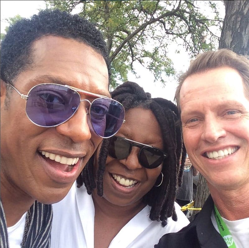 An outdoor selfie under a tree: Beddor grinning beside two
               friends in sunglasses, all three cheek to cheek.
