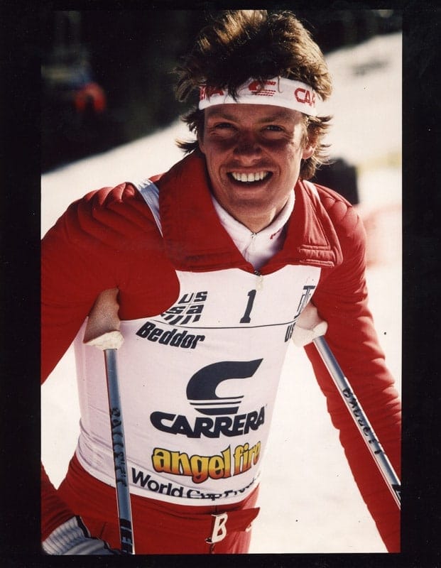 Beddor at the Angel Fire World Cup, leaning on his poles and
               laughing into the camera in a red suit and headband. His bib reads
               USA, Beddor, number one, over Carrera and Angel Fire World Cup
               patches.