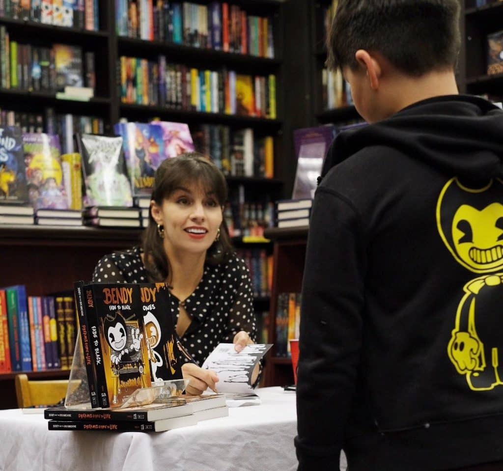 Author Adrienne Kress signing a copy of "Bendy: Fade to Black" for a young fan. 