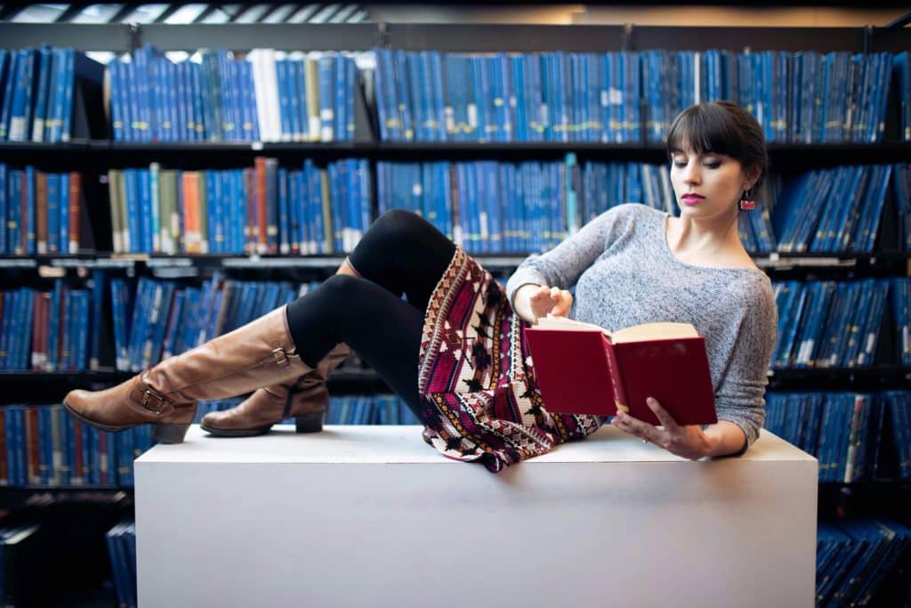 Author Adrienne Kress reclining on a table and reading a book. 