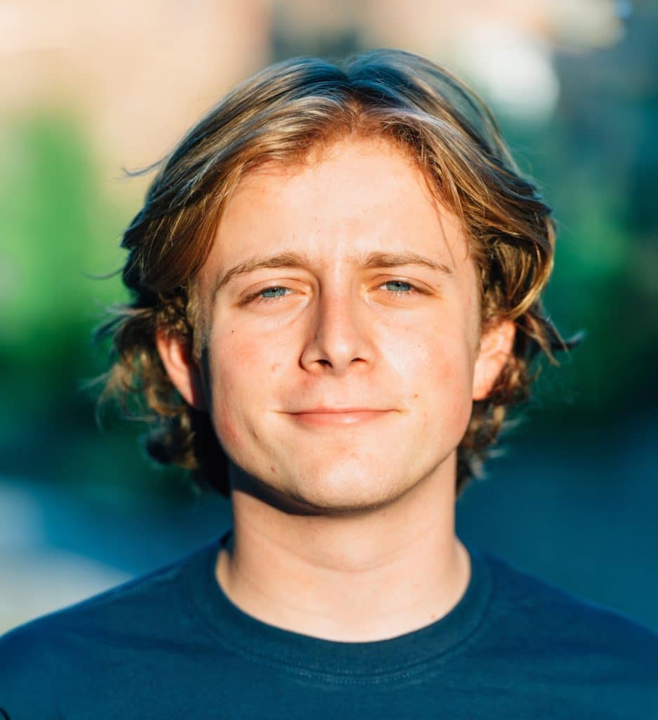 Jake Curtis in a blue shirt, against a plain wall.