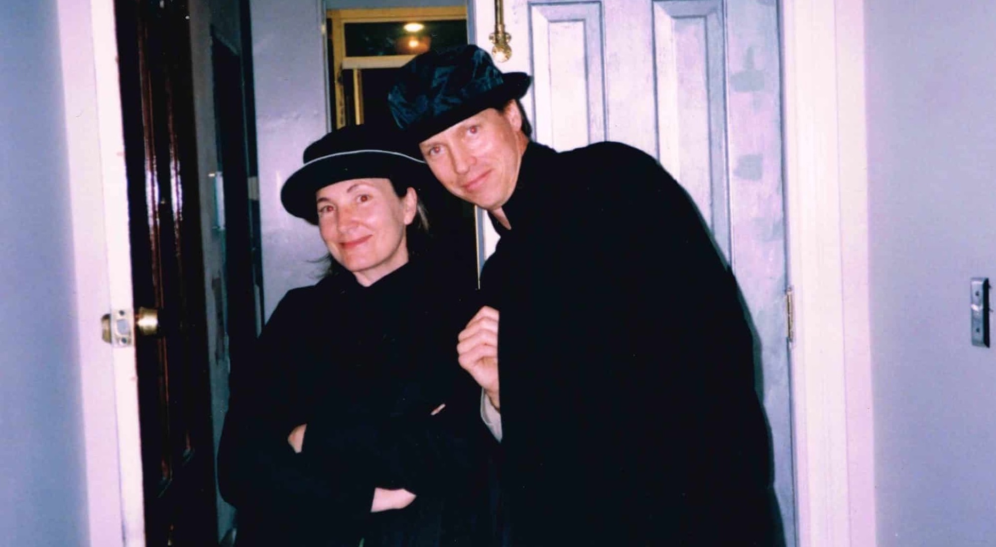 Liz Cavalier and Frank Beddor crowded into a doorway, both in
                black coats and black hats, leaning their heads together and
                smiling at the camera.