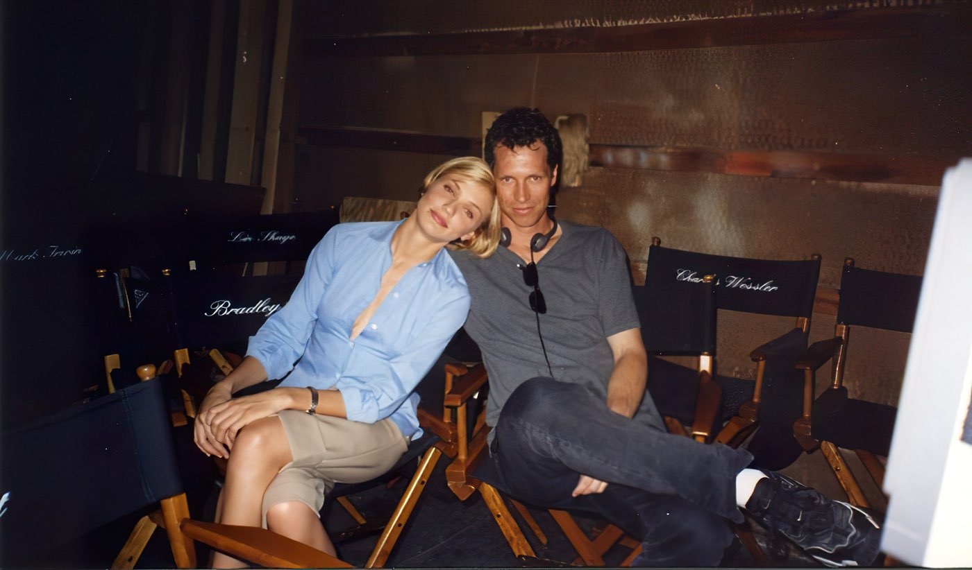 Frank Beddor and Cameron Diaz between takes, sitting together
                    in canvas chairs on a darkened set with her head resting on
                    his shoulder. The empty chairs around them carry the other
                    producers&rsquo; names.