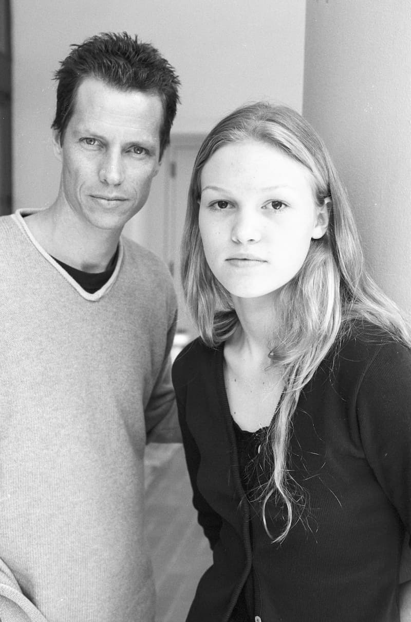 A black-and-white portrait of Frank Beddor and Julia Stiles
               standing together in a hallway, both looking straight into the
               camera without smiling.