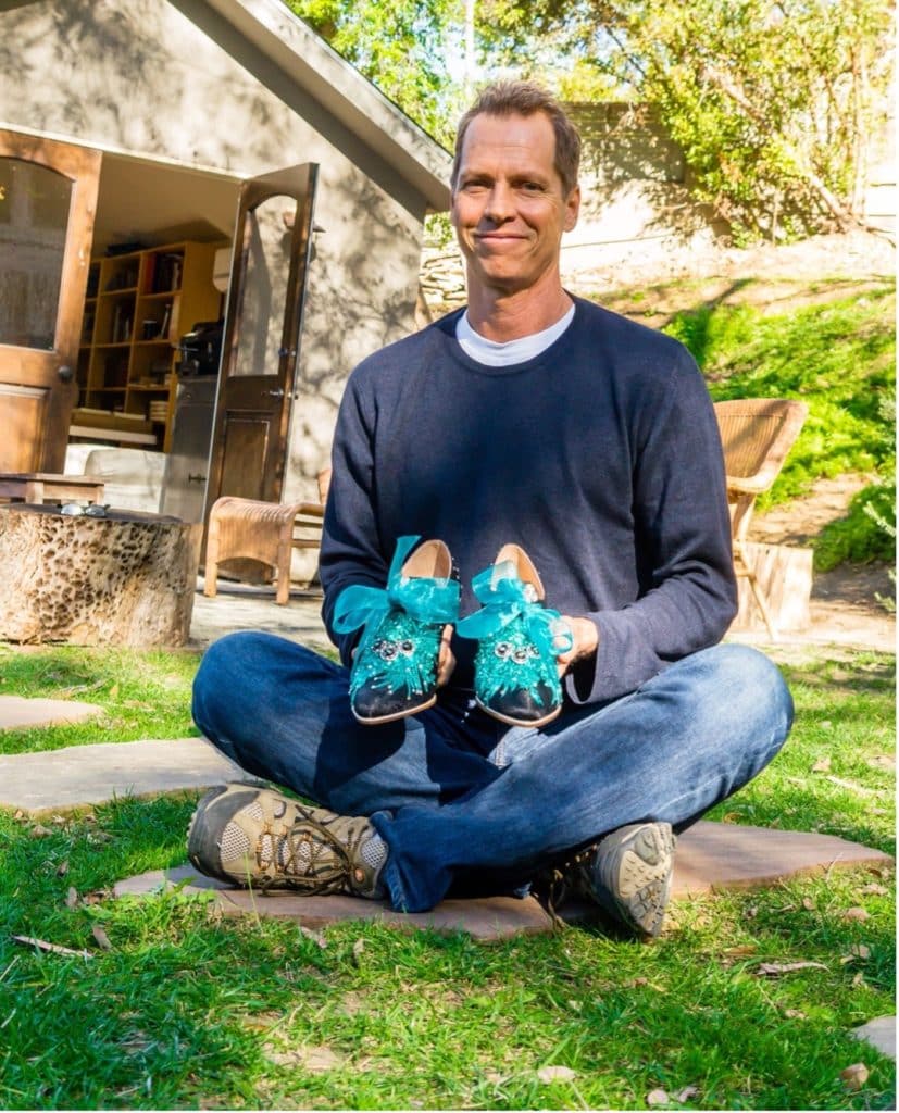 Frank Beddor holds custom shoes made for Whoopi Goldberg, made by Chad Evett in black and light blue.