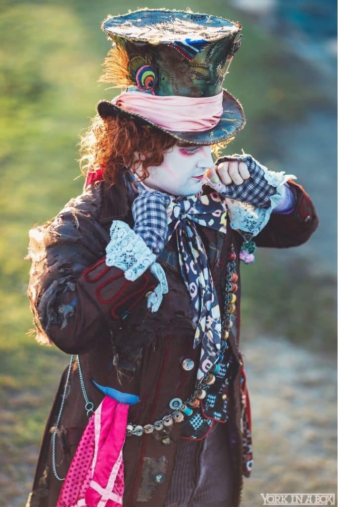 In this image, Chad Evett, sporting a whimsical Mad Hatter outfit, is seen looking deep in thought, suggesting that he is working on something challenging.