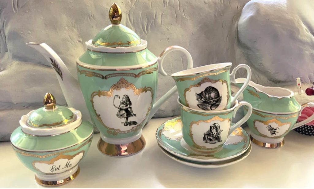 Teapots-and-tea-cups-on-a-shelf-classic-John-Tenniel-Alice-in-Wonderland-illustrations-sugar-bowl-gold-accents-on-mint-green-and-white-porcelain-with-pencil-drawings-of-classic-characters