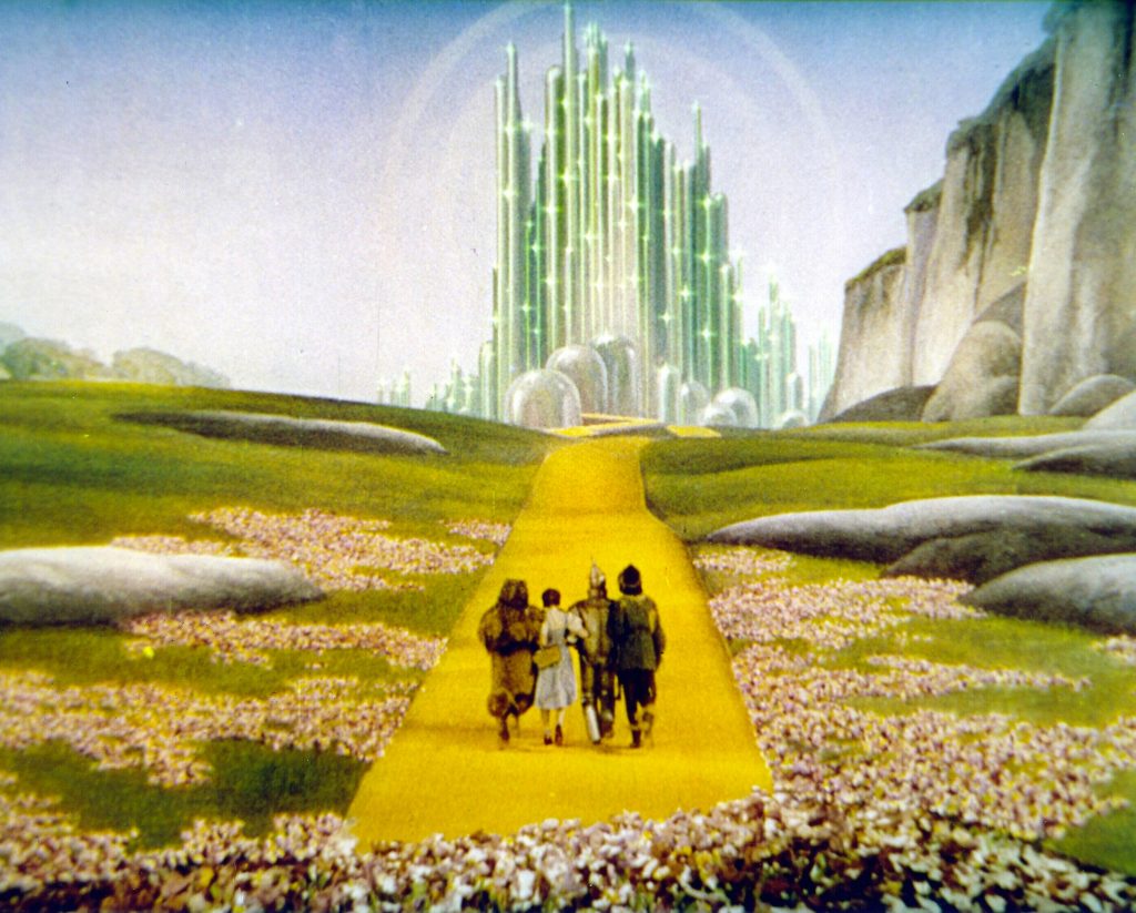 Image of Dorothy Gale, the Cowardly Lion, Scarecrow and the Tin Man walking down the yellow brick road, towards the Royal Palace of Oz, with The Emerald Throne Room, or Royal Chamber. 