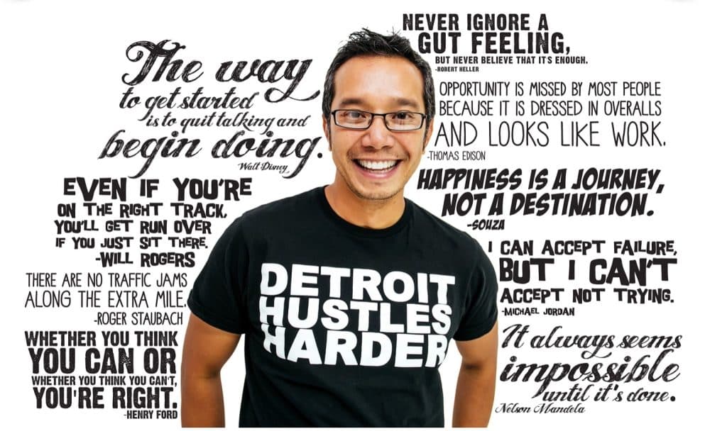 Fernando Del Rosario smiling in front of a white wall of inspiring quotes written in different fonts, with black lettering. Quotes by Thomas Edison, Michael Jordan, Henry Ford, Will Rogers and more. 