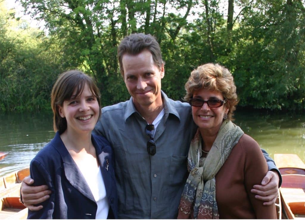 Cally Poplar, Frank Beddor and Barbara Marshall, standing together on a dock, in front of a river, under some green trees. 