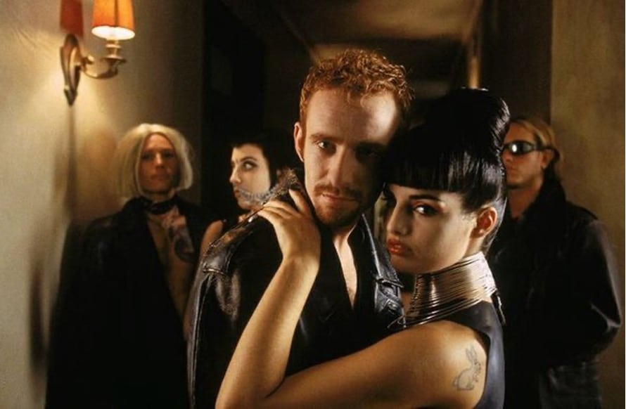 Image of characters from The Matrix, standing in a hallway. The White Rabbit Tattoo is visible on the woman's shoulder