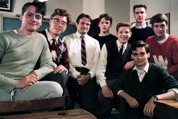 Actor and comedian, Robin Williams, standing in the center of a group of young men posing for a photo. From the set of Dead Poet's Society. 