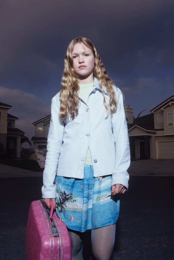 Publicity photograph of Julia Stiles, wearing a blue jacket and carrying a pink suitcase, for the 1998 thriller "Wicked". 
