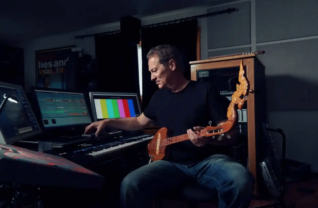 "Wicked" composer Cliff Martinez in his studio, working with a guitar, keyboard, and software interface. 