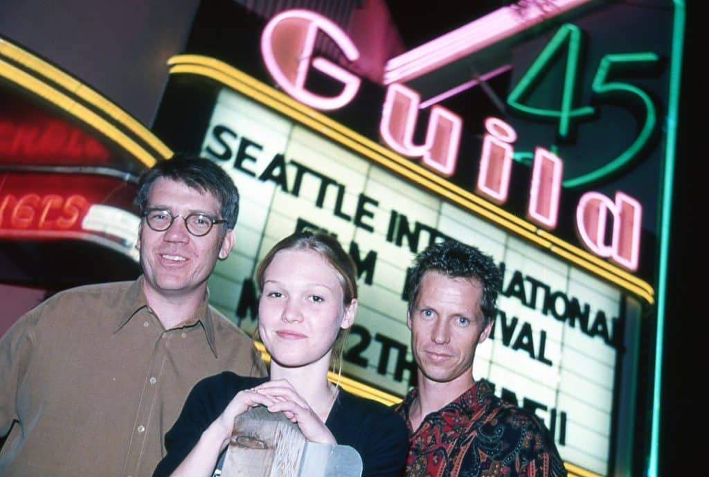 Image of Julia Stiles, director Michael Steinberg, and producer Frank Beddor standing in front of a movie theater marquee at the Seattle International Film Festival. 
