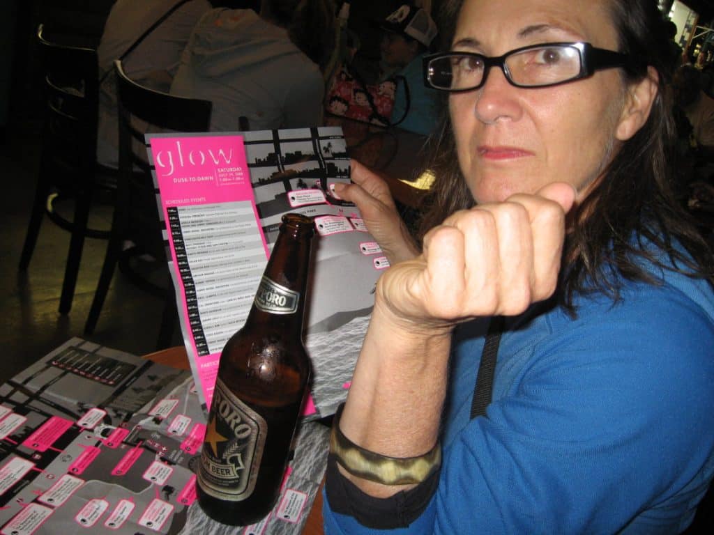 Author Liz Cavalier holding a pink and grey guide map with a bottle of Sapporo beer in the foreground. 