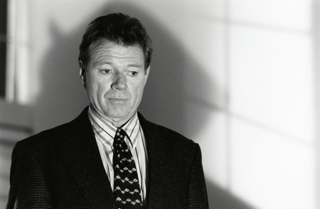 Still black and white image from the thriller movie "Wicked" featuring Michael Parks in a suit and tie. 