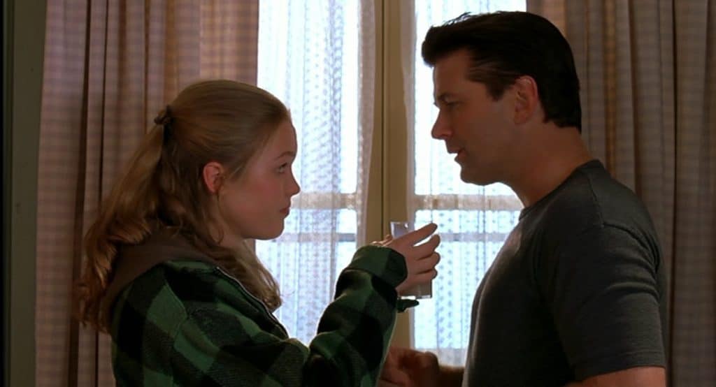 Still image of Julia Stiles and Alec Baldwin in front of a window from the 2000 David Mamet dark comedy film "State and Main".