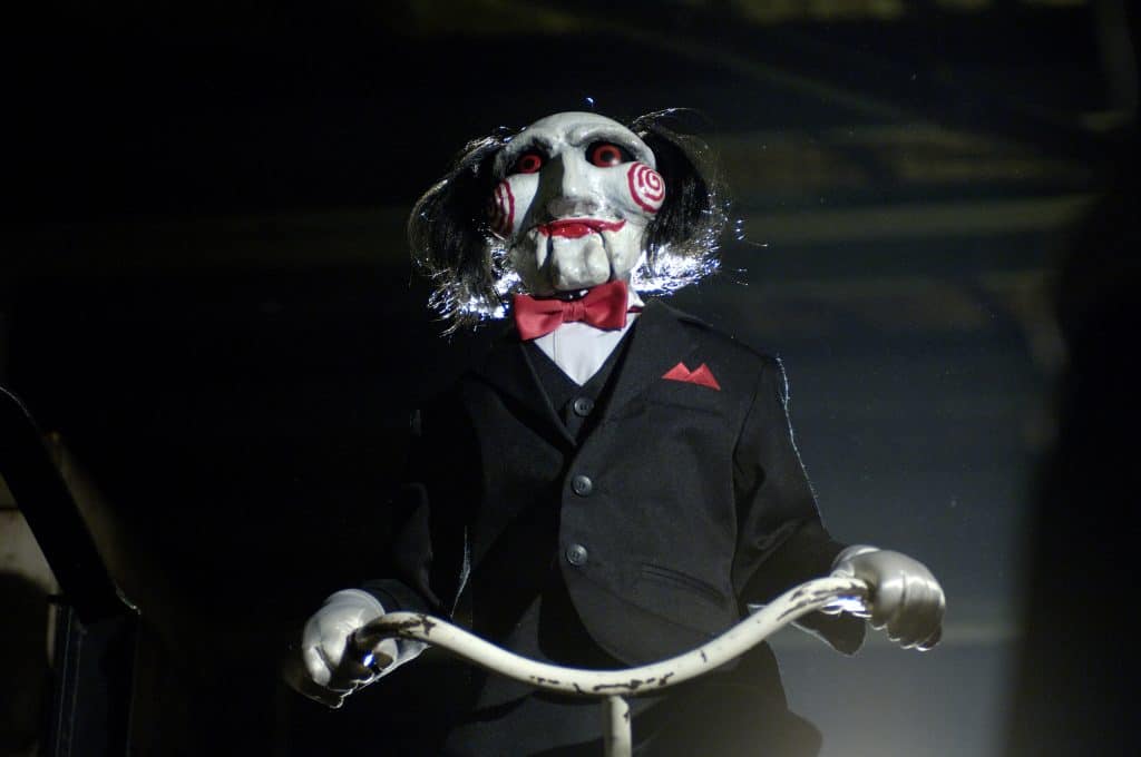 Still image of Billy the Puppet riding a tricycle in the 2004 horror film "Saw" directed by James Wan. 