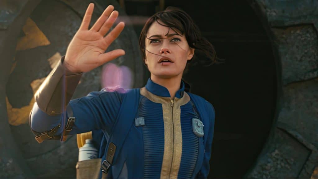 Still image from the Amazon post-apocalyptic drama series "Fallout" featuring Ella Purnell as Lucy MacLean wearing a blue and gold jumpsuit. 