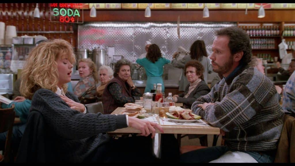 Still image from Rob Reiner's 1989 romantic comedy film "When Harry Met Sally" featuring Billy Crystal and Meg Ryan in a diner. 