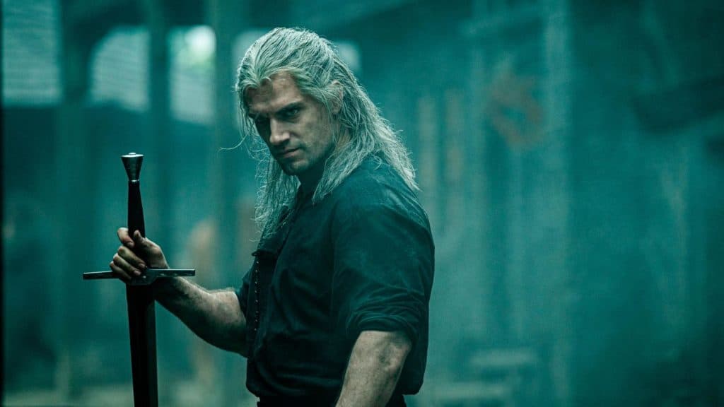 Still image of Henry Cavill as Geralt of Rivia holding a sword from the Netflix fantasy drama series "The Witcher".