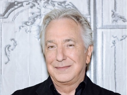 Photograph of actor Alan Rickman wearing a black collared shirt in front of a white background. 