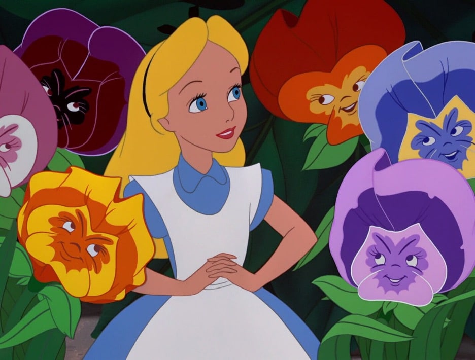 Still image of Alice in a blue dress and white apron surrounded by smiling, anthropomorphic flowers from the 1951 Disney animated film "Alice in Wonderland". 