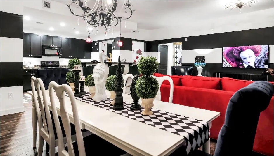 A kitchen and dining room with black-and-white wallpaper, white table, and black cabinets from the Alice's Palace Airbnb in St. Augustine, Florida. 