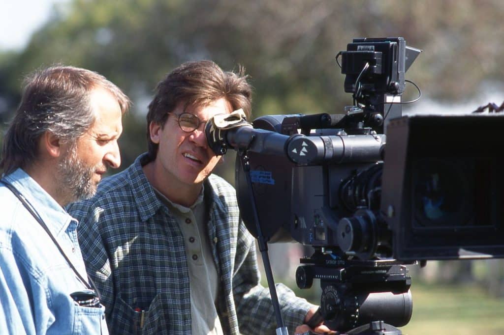 Photograph of director Michael Steinberg looking through the viewfinder of a film camera on the set of the 1998 thriller "Wicked". 