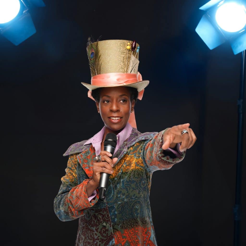 A photograph of wellness educator and opera singer Dr. April James holding a microphone and wearing a gold top hat. 