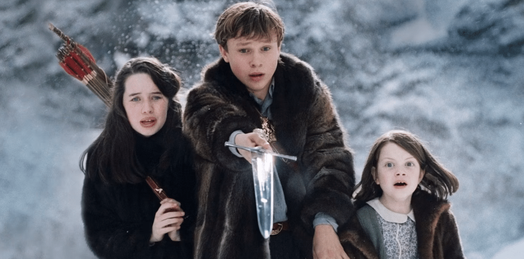 Still image from the 2005 high fantasy film "The Chronicles of Narnia: The Lion, the Witch, and the Wardrobe" featuring Georgie Henley, Anna Popplewell with a bow and arrows on her back, and William Moseley holding a sword.