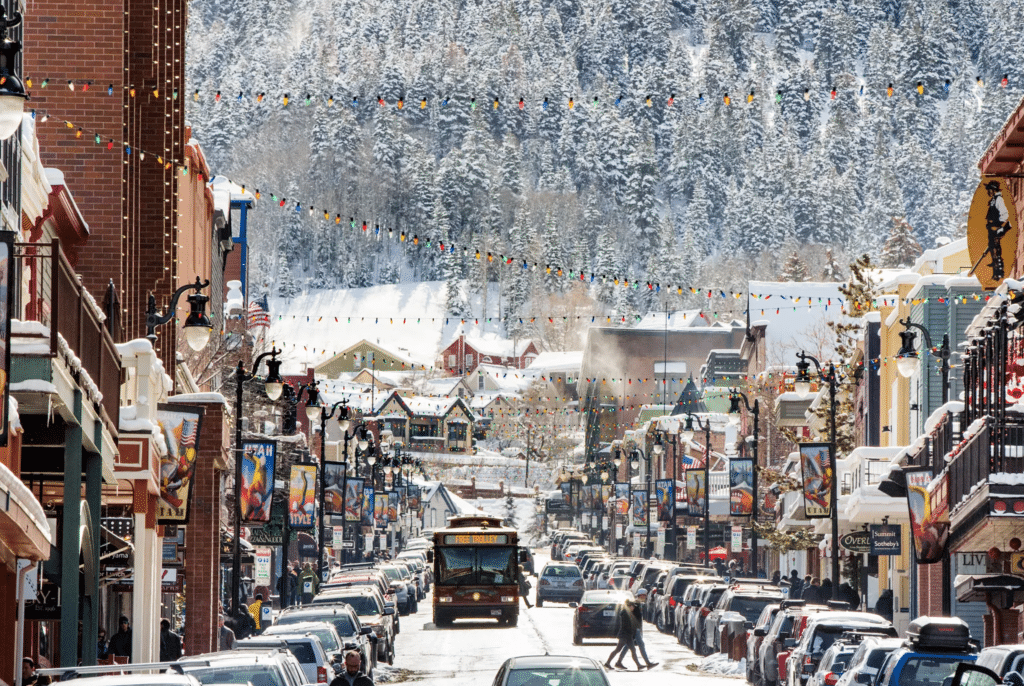 A photograph of Main Street in Park City, Utah during winter with a forested mountain in the background. 