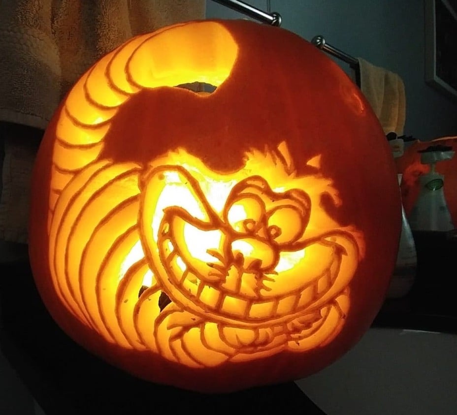 A photograph of a pumpkin carved to depict the Cheshire Cat from "Alice in Wonderland". 